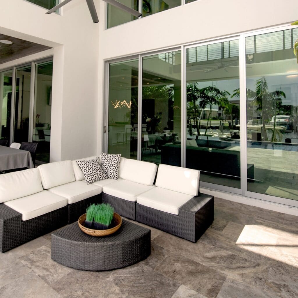 A large outside patio, with white furniture and table with a potted plant.