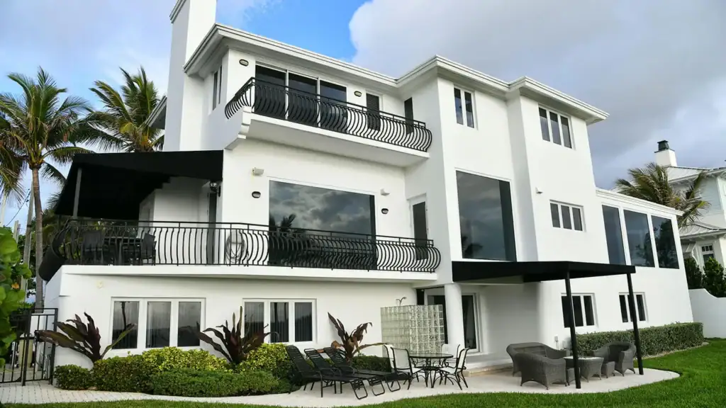 large white house with multiple windows, surrounded by palm trees