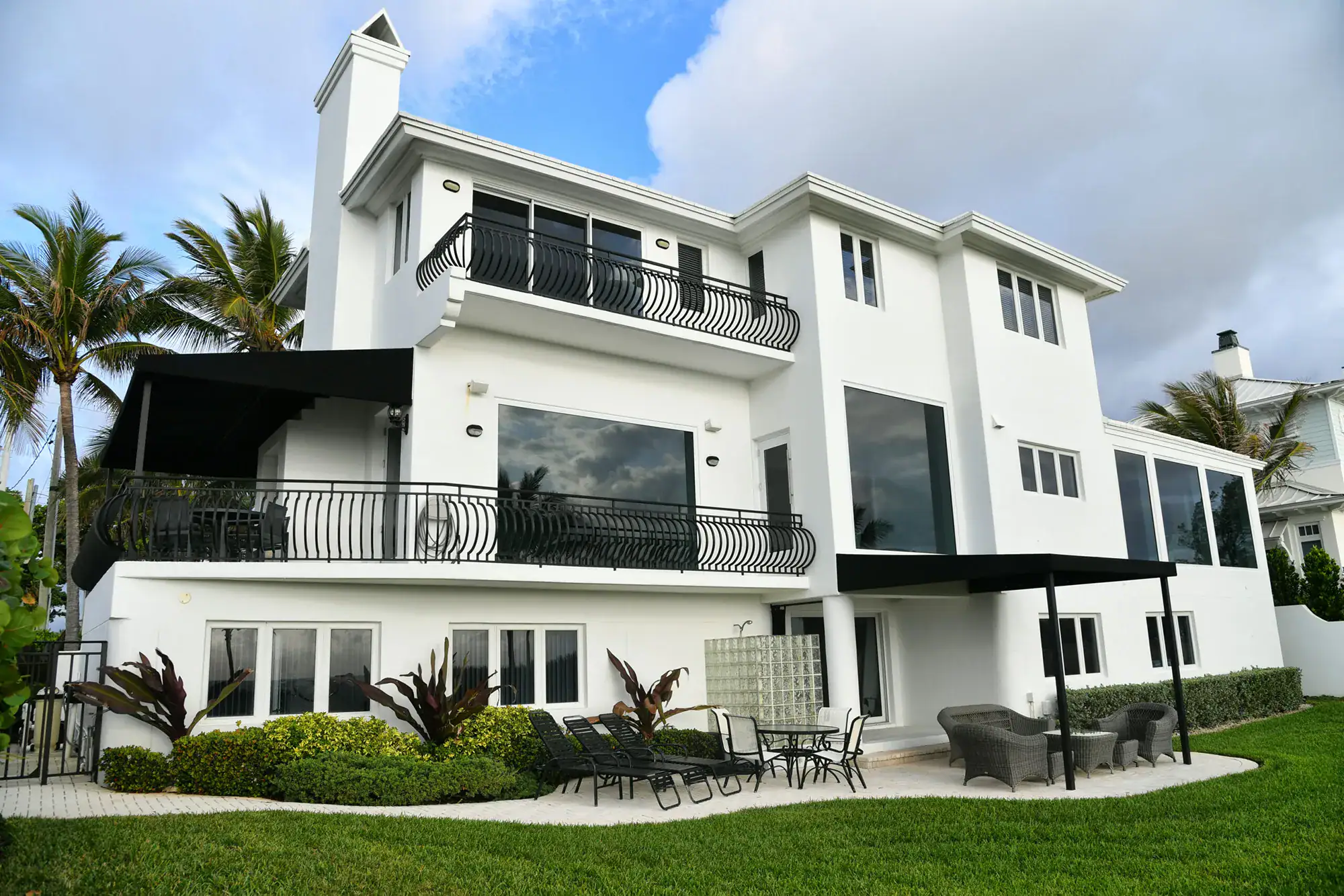 large white house with multiple windows, surrounded by palm trees