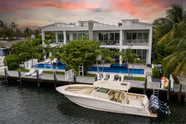view from waterfront looking at boat docked in front of large house